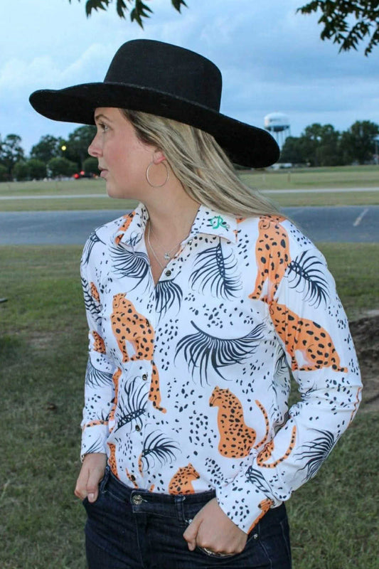 Savanna Streak barrel racing show shirt with orange cheetah print and black palm accents on white, button-down closure, and long sleeves, styled with jeans and a black hat.