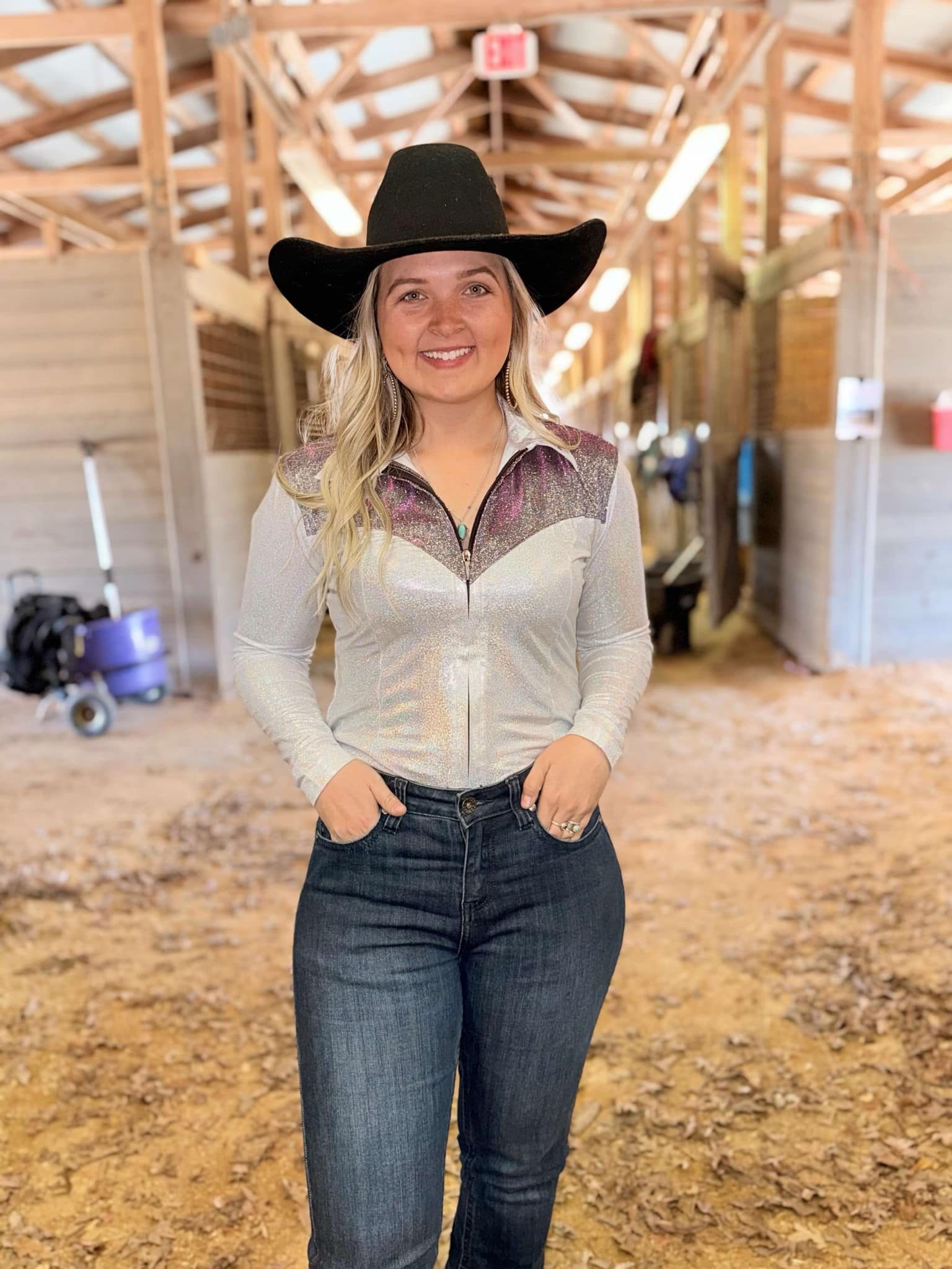 Barrel racer wearing the Stardust Shimmer Show Shirt in a barn, showcasing its dynamic color-shifting fabric.